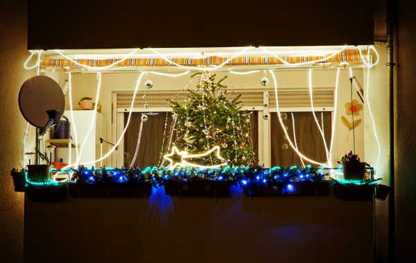 Symbolbild: grell erleuchteter, weihnachtlich geschmückter Balkon