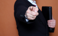 Symbolbild Abberufung des Verwalters: Mann im Anzug weist per Fingerzeig zum Ausgang