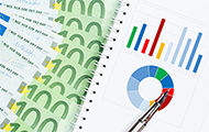 Symbol-Bild für die Kostenaufteilung in einer WEG: aufgefächerte 100-Euro-Scheine neben einer Statistik mit Kuchengrafik