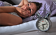 Symbol-Bild für Ängste: Frau liegt nachts im Bett wach, weil sie sich offenbar sorgt. Der Wecker steht auf 2.30 Uhr.